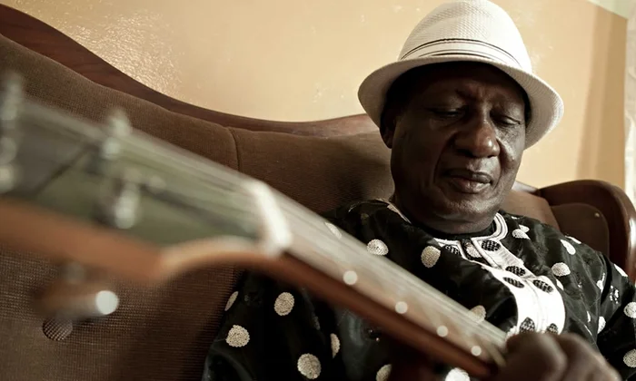 legendary Ghanaian musician Ebo Taylor playing guitar, highlighting his fusion of highlife, funk, and jazz that shaped Afrobeat.