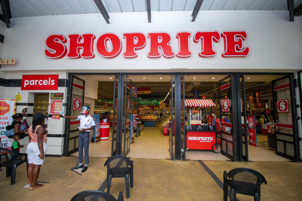 Shoppers walking past the entrance of a large retail supermarket in Ghana.