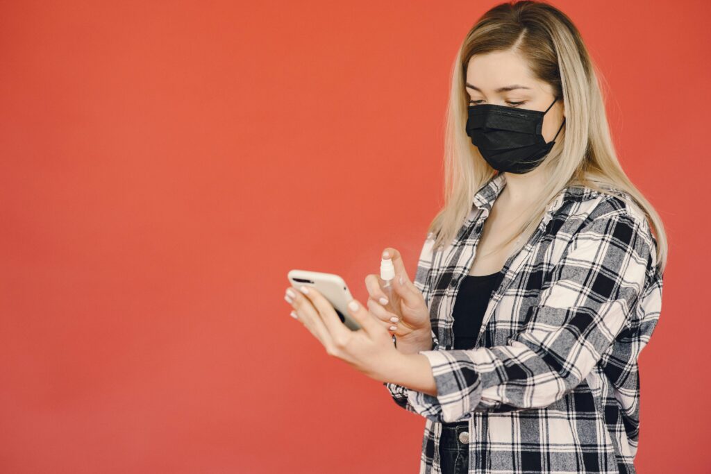 Person holding a smartphone with multiple warning icons around it, illustrating potential hazards such as eye strain, distraction, and radiation exposure.
