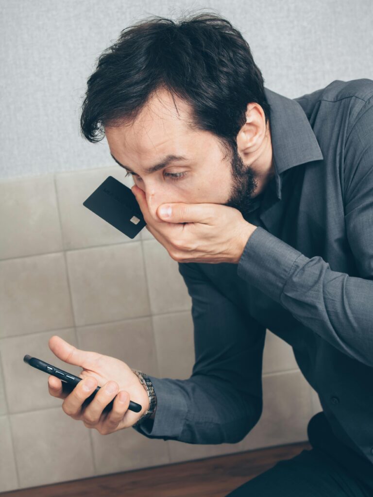 A young Ghanaian looking worried at his smartphone, symbolizing online scams.