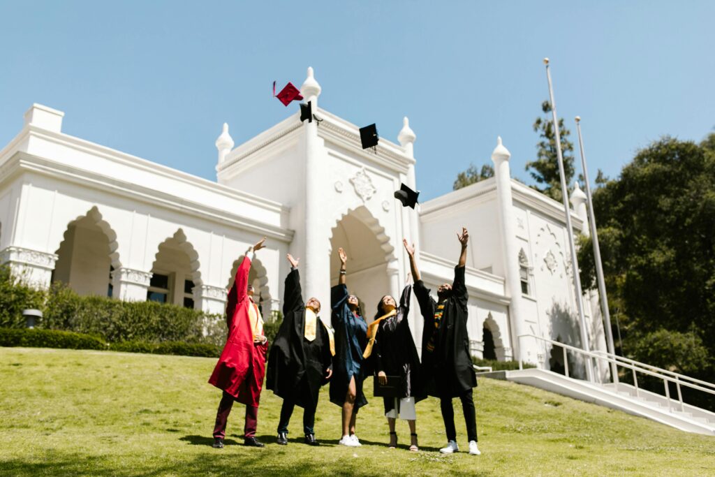 Group of international students celebrating graduation by tossing their caps into the air.