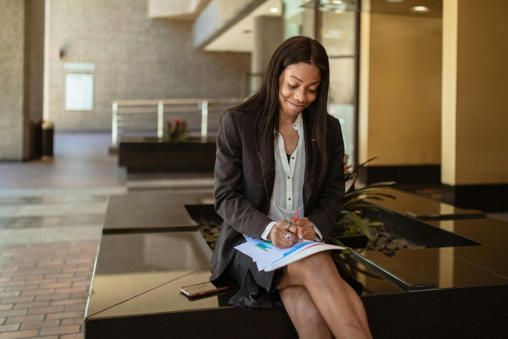 Young African entrepreneur confidently using her smartphone for online business with secure authentication.