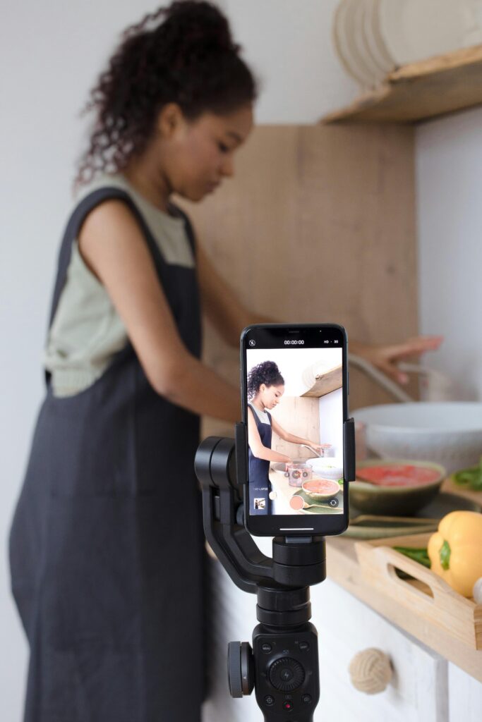A young Ghanaian content creator recording a video on her smartphone for social media.
